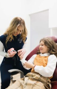 Cara Dentistry team teaching young girl how to properly brush teeth